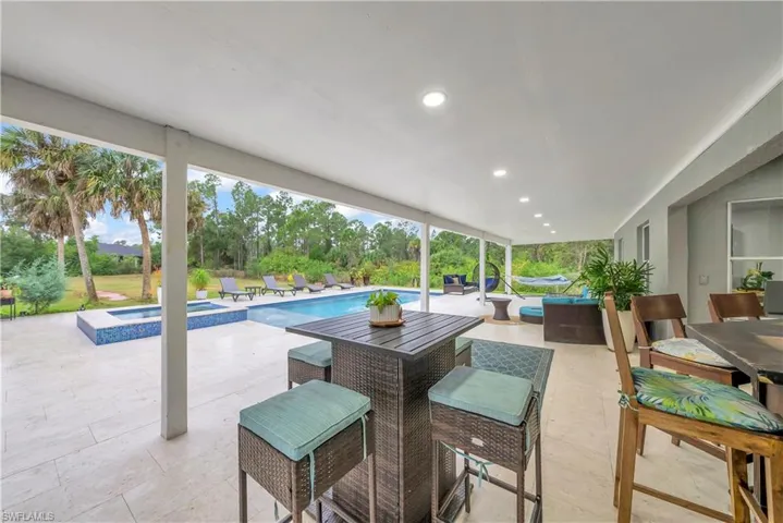 View of patio featuring outdoor dining space and a pool with connected hot tub