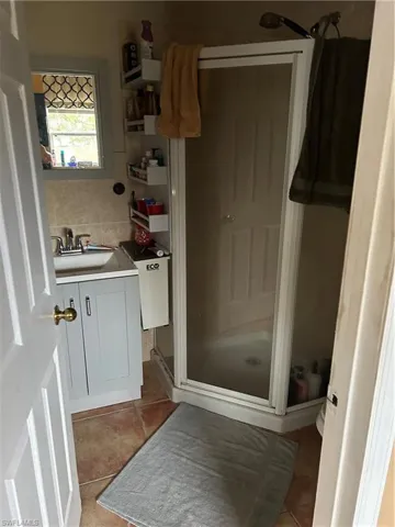 Full bath featuring a stall shower, vanity, decorative backsplash, and light tile patterned flooring