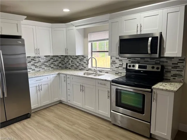 Kitchen featuring stainless steel appliances, white cabinets, light stone countertops, and recessed lighting