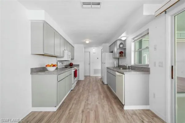 Kitchen featuring gray cabinetry, white appliances, and light wood-type flooring