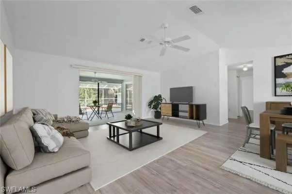 Living room with ceiling fan, light hardwood / wood-style floors, and lofted ceiling, virtually Staged