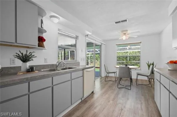 Kitchen featuring white dishwasher, light hardwood / wood-style floors, sink, and ceiling fan, virtualy staged