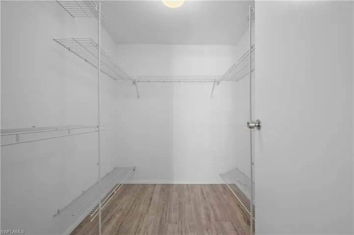 Walk in closet featuring light  in primary bedroom hardwood / wood-style floors