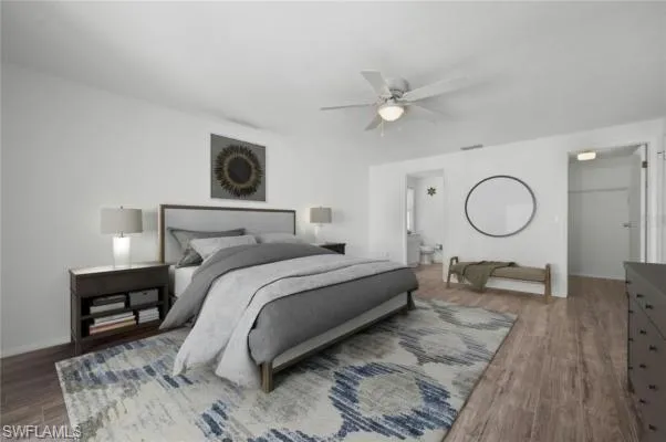 Primary Bedroom featuring a closet, ensuite bathroom, ceiling fan, hardwood / wood-style floors, and a walk in closet, virtually staged