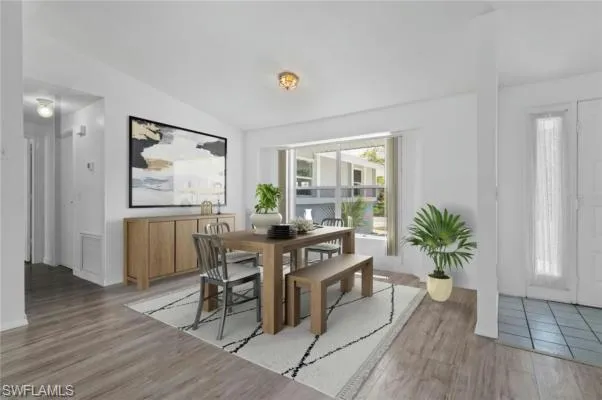 Dining room featuring vaulted ceiling and wood-type flooring, virtually staged