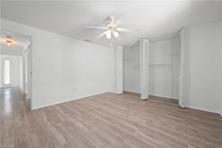 Unfurnished bedroom featuring two closets, ceiling fan, and light wood-type flooring