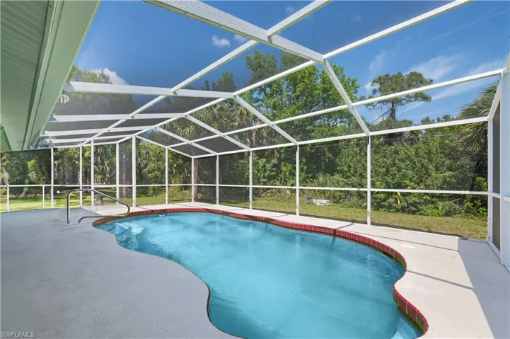 View of swimming pool with a patio and screened enclosure