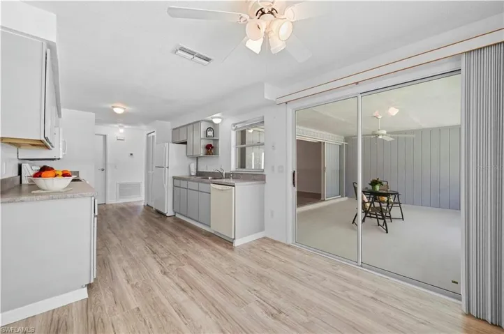 Kitchen with light hardwood / wood-style floors, white appliances, and ceiling fan