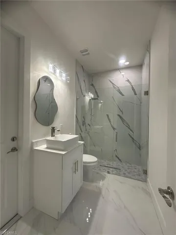 Bathroom featuring vanity, visible vents, a marble finish shower, toilet, and marble finish floor