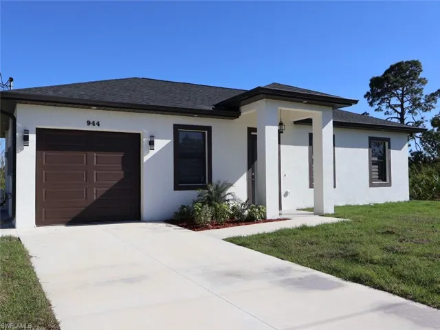 Prairie-style house with a shingled roof, concrete driveway, a front yard, stucco siding, and a garage