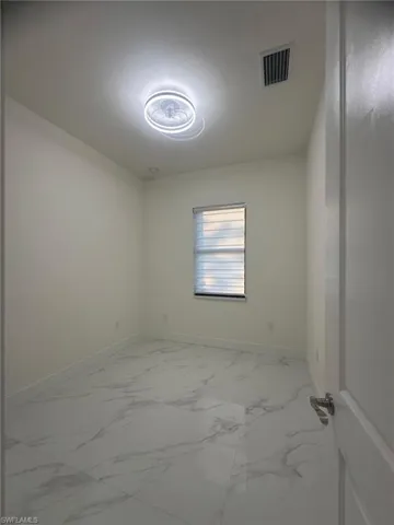 Empty room featuring visible vents, baseboards, and marble finish floor
