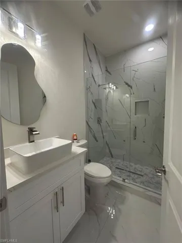 Full bathroom with vanity, visible vents, a marble finish shower, toilet, and marble finish floor