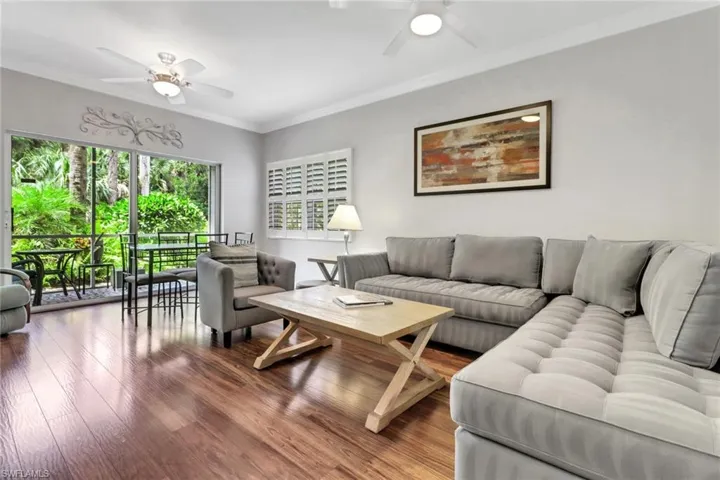 Living room with a ceiling fan, wood finished floors, and crown molding