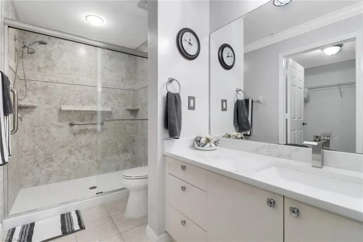 Full bathroom with toilet, a shower stall, tile patterned flooring, vanity, and ornamental molding