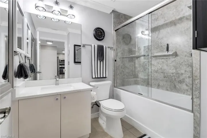 Full bath with crown molding, toilet, vanity, tile patterned floors, and enclosed tub / shower combo