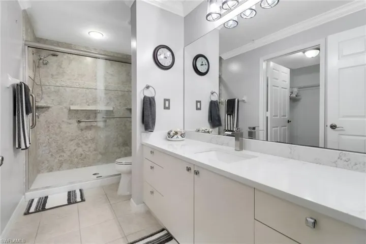 Bathroom with toilet, a stall shower, vanity, crown molding, and baseboards