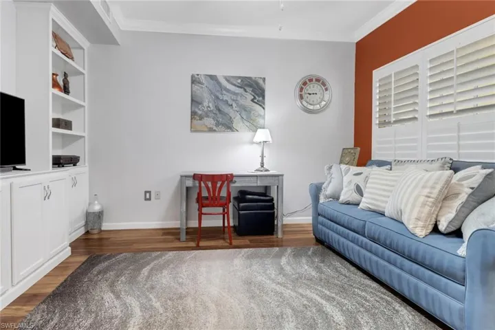 Living room featuring wood finished floors, ornamental molding, and baseboards
