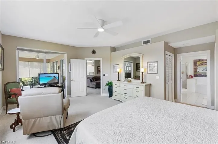 Bedroom with ceiling fan, connected bathroom, and light carpet