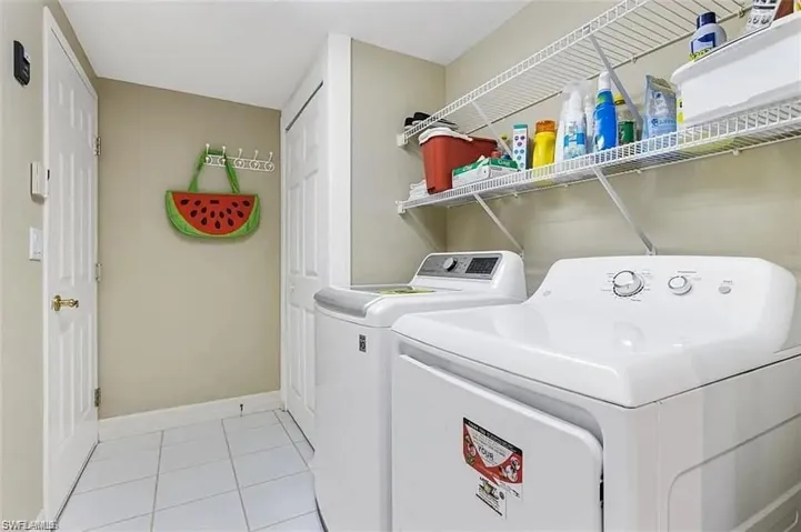 Laundry area with washing machine and dryer and light tile patterned flooring