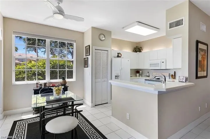 Kitchen with white appliances, white cabinetry, light tile patterned flooring, and ceiling fan