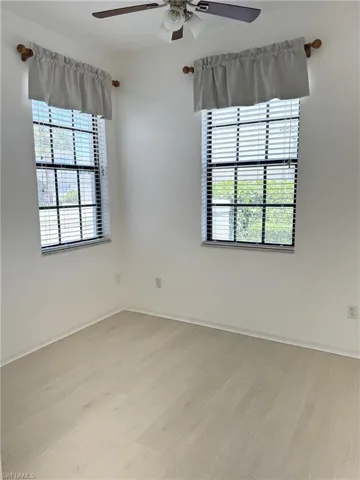 Spare room featuring a ceiling fan, baseboards, and light wood-type flooring