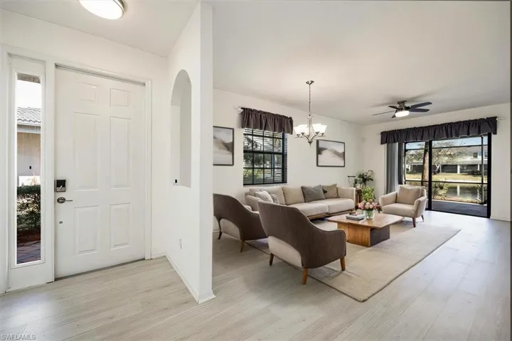 AI Staged - Entrance foyer featuring light wood-style floors, arched walkways, a healthy amount of sunlight, and ceiling fan with notable chandelier
