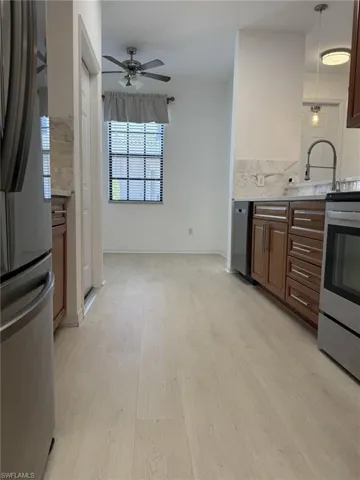 Kitchen featuring stainless steel appliances, ceiling fan, light wood-type flooring, light countertops, and hanging light fixtures