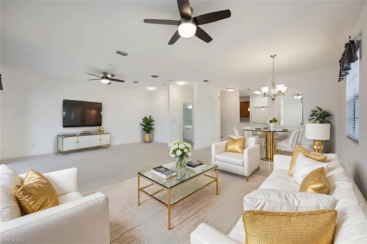 Living room featuring ceiling fan with notable chandelier, visible vents, and light wood-style flooring