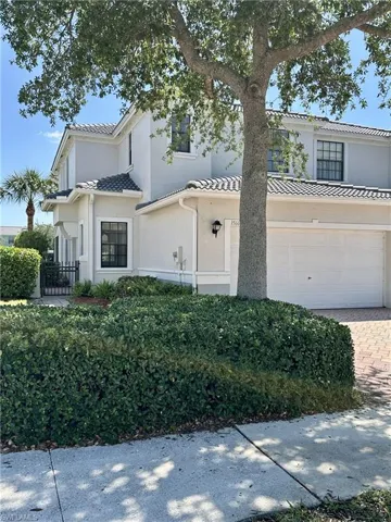 View of front facade featuring driveway, stucco siding, a tile roof, and an attached garage