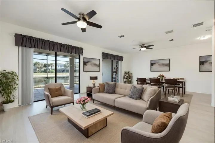 AI Staged - Living area featuring light wood-type flooring, visible vents, and a water view