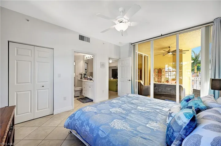 Bedroom featuring light tile patterned floors, ceiling fan, ensuite bathroom, and access to outside