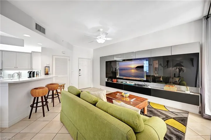 Living room with a ceiling fan and light tile patterned flooring