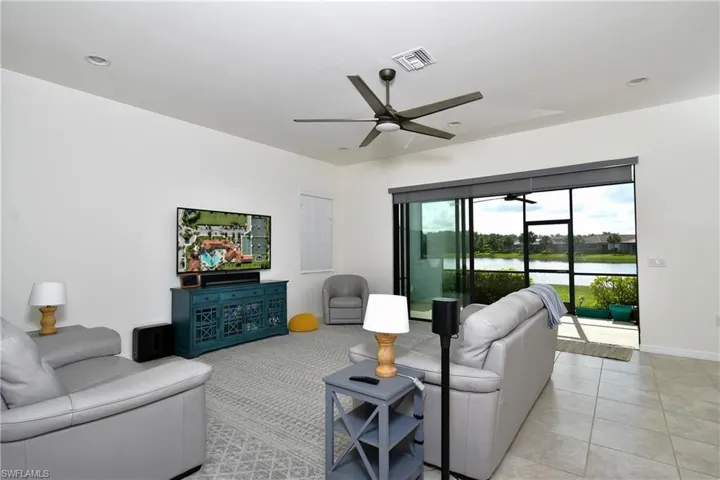 Living room with ceiling fan, light tile flooring, and a water view