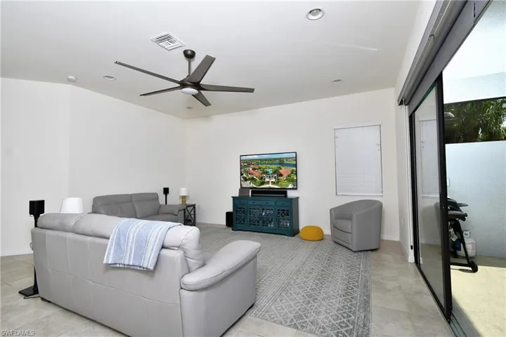 Living room with ceiling fan and light tile floors