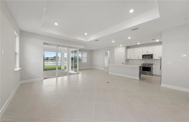 Unfurnished living room featuring a raised ceiling and light tile patterned flooring