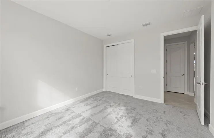 Unfurnished bedroom with light colored carpet and a closet