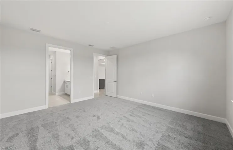 Unfurnished bedroom with ensuite bath and light colored carpet