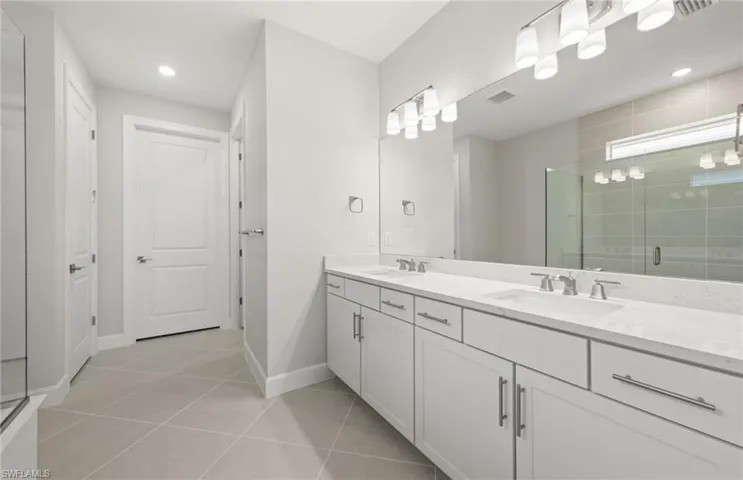 Bathroom with a shower with door, vanity, and tile patterned floors
