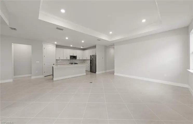 Unfurnished living room featuring a raised ceiling and light tile patterned floors