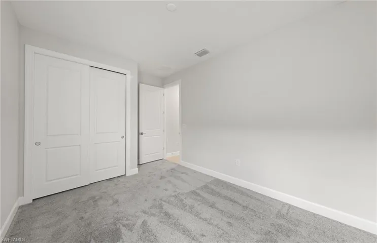 Unfurnished bedroom with light colored carpet and a closet