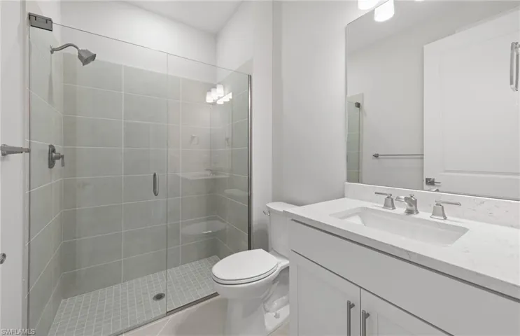 Bathroom featuring vanity, toilet, tile patterned flooring, and a shower with door