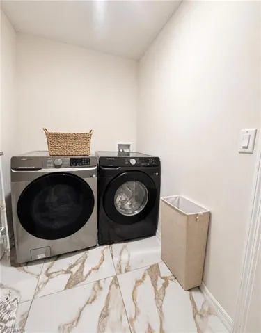 Laundry area featuring durable tile flooring, light-toned walls, and a front-loading washer and dryer