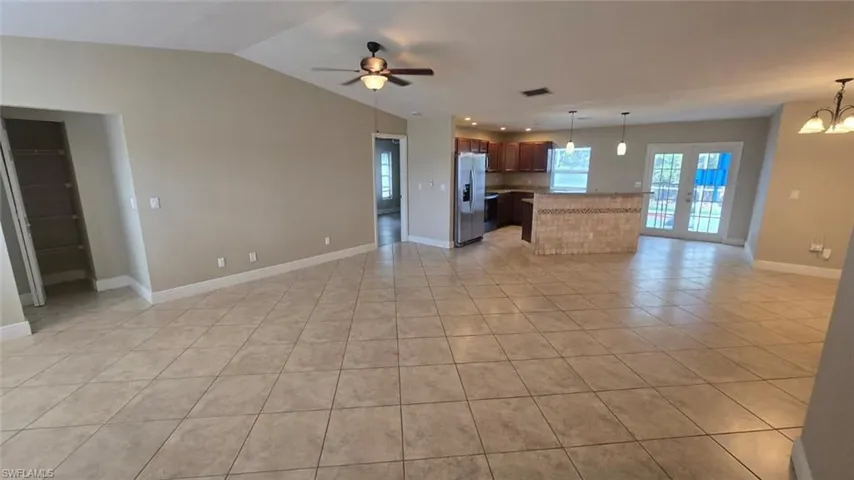 living room with light tile patterned flooring, a chandelier, a ceiling fan, vaulted ceiling, and french doors