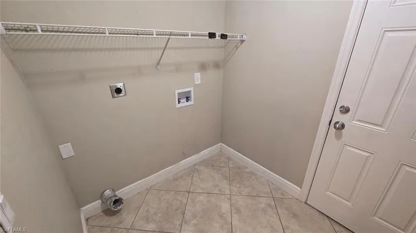 Laundry room with hookup for an electric dryer, washer hookup, and light tile patterned flooring