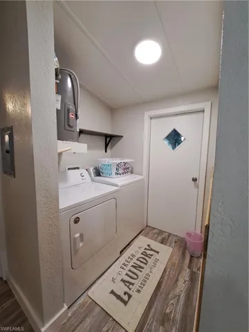 Washroom with dark hardwood / wood-style floors and washing machine and dryer