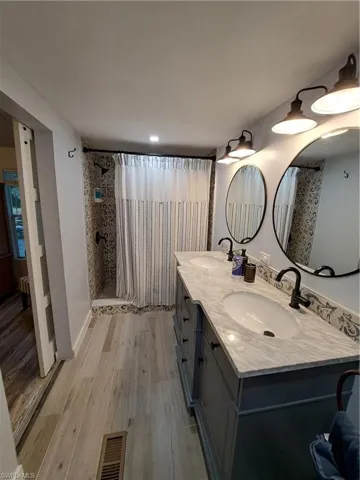 Bathroom with a shower with curtain, dual sinks, hardwood / wood-style floors, and oversized vanity