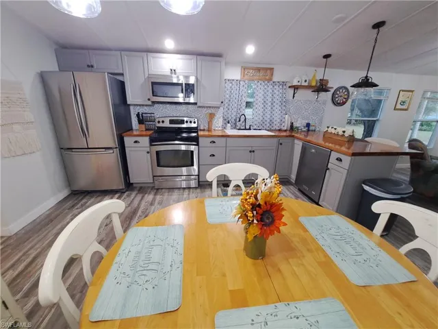 Kitchen with gray cabinetry, appliances with stainless steel finishes, hardwood / wood-style flooring, backsplash, and sink