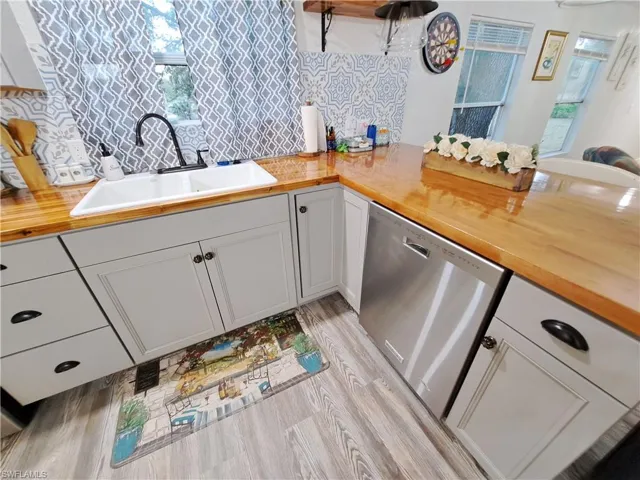 Kitchen featuring dishwasher, sink, wood counters, and light wood-type flooring