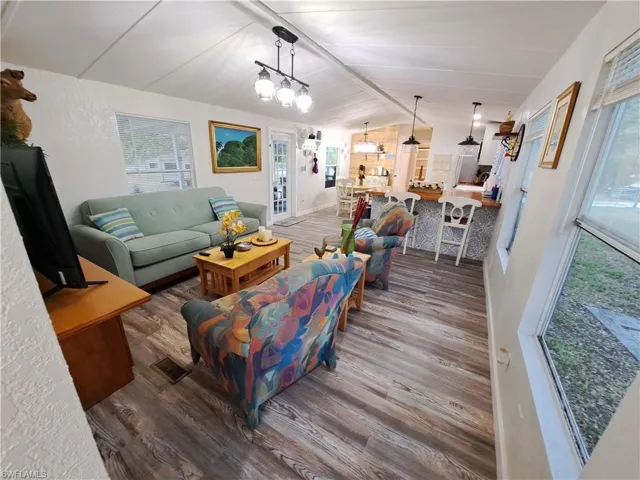 Living room with hardwood / wood-style floors, lofted ceiling, and a chandelier