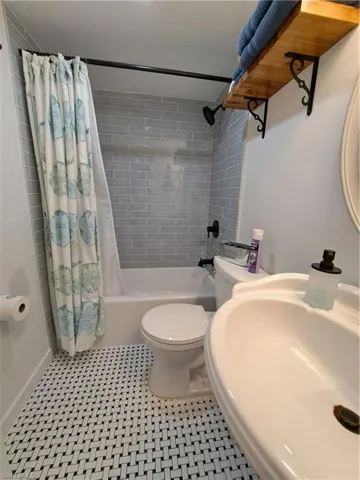 Full bathroom with sink, tile flooring, shower / tub combo, and toilet